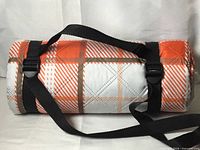 Rolled picnic blanket showing plaid pattern and carry straps