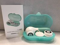 Front view showing cleanser handset in teal case with two spare brush heads and product box