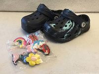 Pair of clogs with sealed bag of charms shown together
