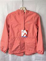 Front view of coral Ripzone girls rain jacket with tags attached