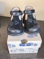 Front view of navy toddler shoes on box showing heart design and size info