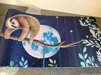 Top view of desk mat showing sloth design, moon and stars