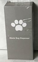 Front of sealed grey retail box labeled Waste Bag Dispenser with paw logo