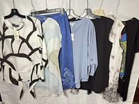 All seven women’s medium garments hanging on rack, fronts visible