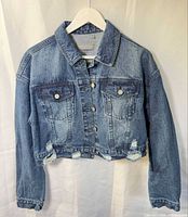 Full view of cropped denim jacket on hanger