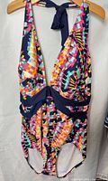 Front view of multicolor geometric print one-piece swimsuit with navy trim and halter tie