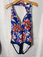 Front view of blue floral deep V halter one-piece swimsuit on hanger showing print and cut
