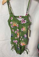 Front view displaying floral print, keyhole, ruched sides, tag attached