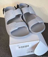 top view of grey rubber slide sandals on box