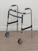 Full view of collapsible walker showing frame, wheels, hand grips and adjustable legs