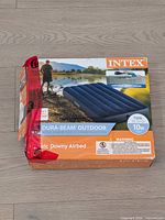 Front view of boxed Intex Dura-Beam Outdoor airbed showing product image and damaged box corner