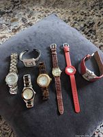 Group shot of seven wristwatches arranged on cushion