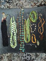 All twelve necklaces and bracelets arranged on cushion