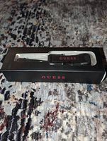 Front of retail box showing GUESS selfie stick through window