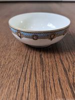 Side view of porcelain bowl showing floral blue band and gold trim