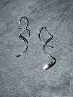Pair of silver-plated spiral earrings displayed on grey fabric background