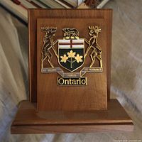 Front view of wooden bookend showing brass and enamel Ontario coat of arms plaque