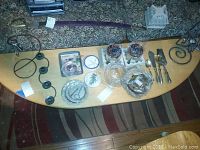 Wide overhead view showing all items on a wooden table including metal candle holders, glass candle holders, cutlery, small white tray, and Voluspa candle packaging.