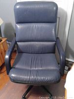 Front view of a black plethora material swivel desk chair showing cushioned seat and backrest with minor wear.