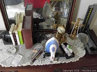 Wide shot of dresser top showing Kunds clock, rhino bookends, books, iron, and various decorative items on a lace cloth