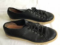 Side view of both sneakers showing perforated leather and beige soles