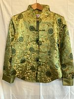 Front view of green and gold silk brocade jacket with frog toggles