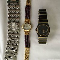 Three wristwatches laid flat showing bracelets and dials