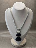 Full view of necklace on display bust showing braided cord and pendant