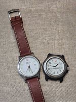 Both watches side by side showing dials, strap on Swiss Military, missing strap on Swiss Army