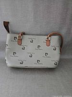 Full view of handbag front showing logo pattern, straps, shape