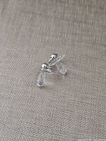Two crystal pacifier charms standing on fabric background