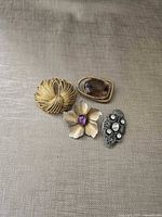 Four brooches laid on fabric showing designs and stones