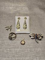 Group shot: damascene earrings on card, dragonfly brooch, snake ring, Saint Benedict pendant, swallow charm