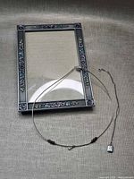 All three items laid out: photo frame, wire choker with beads and dove charm, sterling chain with pendant