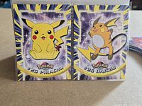 Front view of Pikachu and Raichu Topps cards side by side in sleeves