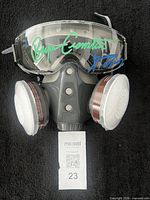Front view of autographed respirator mask with filters and MaxSold tag
