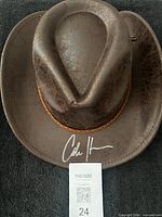 Top view of brown cowboy hat showing signature and braided band
