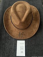 Top view of brown fedora with signature and lot tag