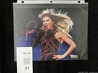 Full signed photograph in protective sleeve with MaxSold label visible