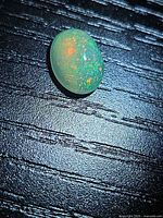 Top view of oval opal cabochon showing colour play