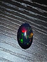 Top view of oval cabochon displaying multicolored flashes