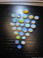 Full parcel of oval opal cabochons arranged on dark surface