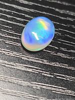Oval opal on dark surface showing play-of-color
