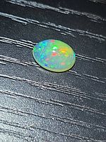 Top view of oval opal showing multicolour fire