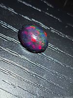 Top view of oval black opal showing multicolour play