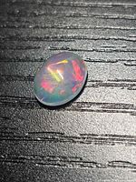 Top view of oval cabochon jelly opal showing play of colour