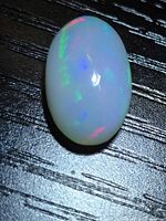 Top view of oval crystal fire opal showing multicolour flashes