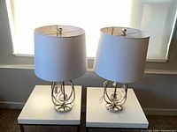 Full view of both chrome table lamps on white tables