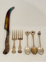 Full view of cheese knife, 2 forks, 3 souvenir spoons