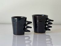 Front view of both ceramic mugs showing size difference and spiral handles